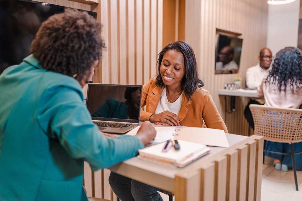 Person reviewing several bank account balances and a household budget beside a laptop and calculator.